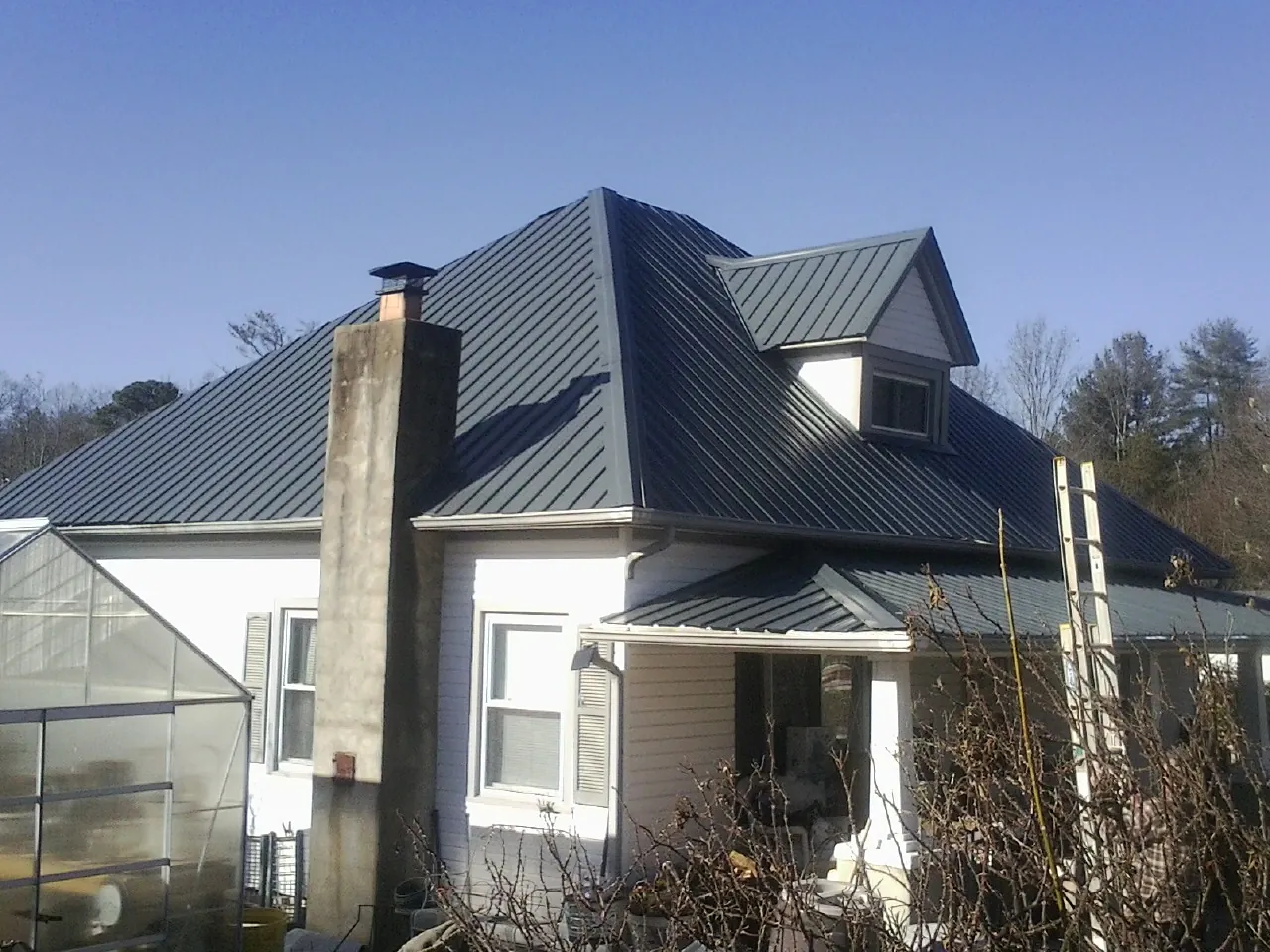 Dark blue standing seam metal roof on a white farmhouse with dormer — Slate & Tile Roof Repair by Roofing Brothers in Waltersburg