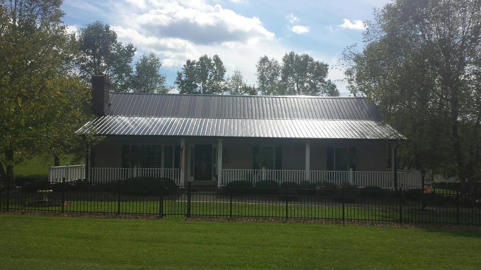 Gray metal roof on a brick ranch with a full width front porch — Gutter Guard Installation work by our crew in Waltersburg
