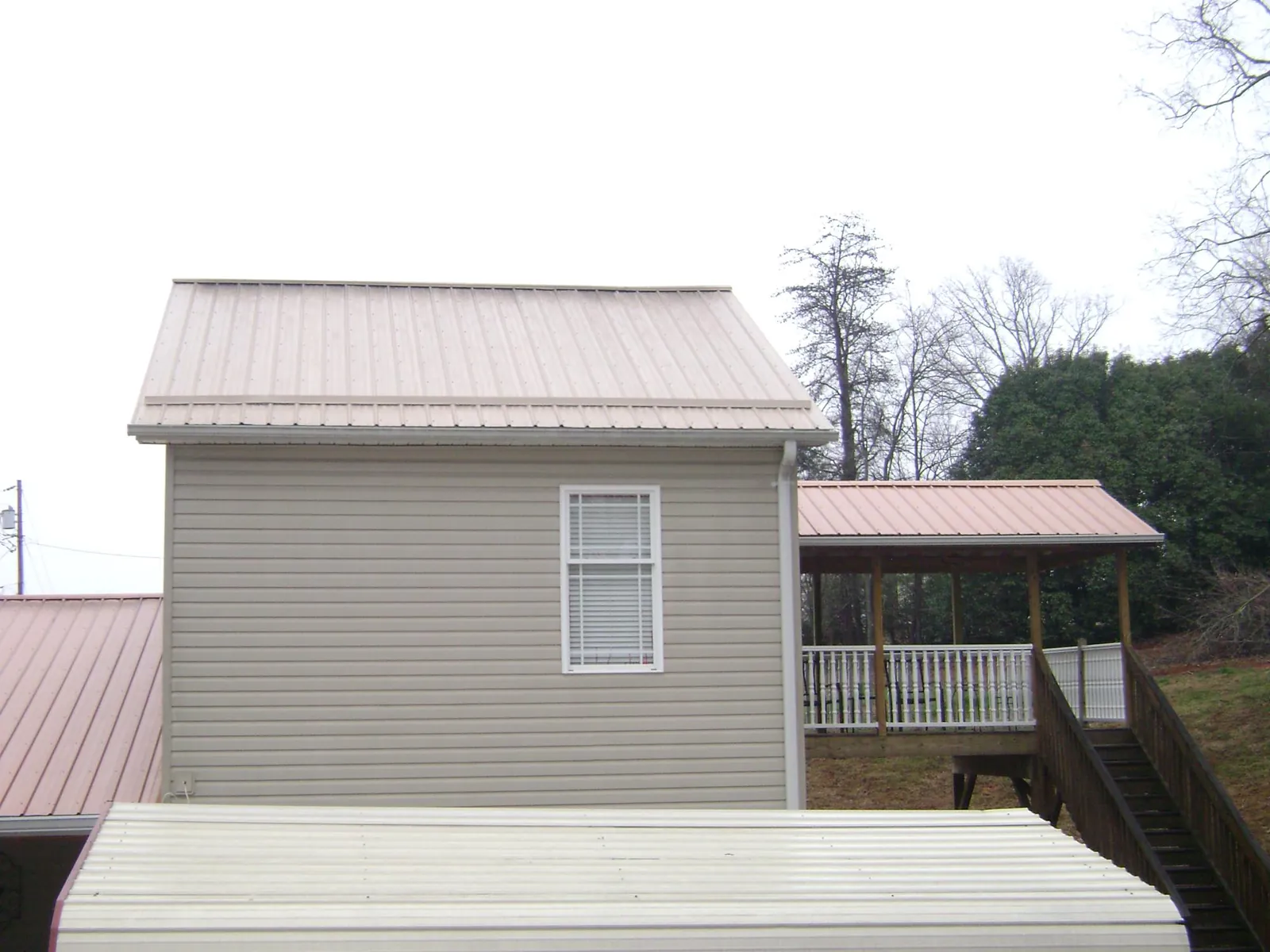 Tan metal roofs on a two story addition and attached porch, from a Roof Replacement job in Waltersburg