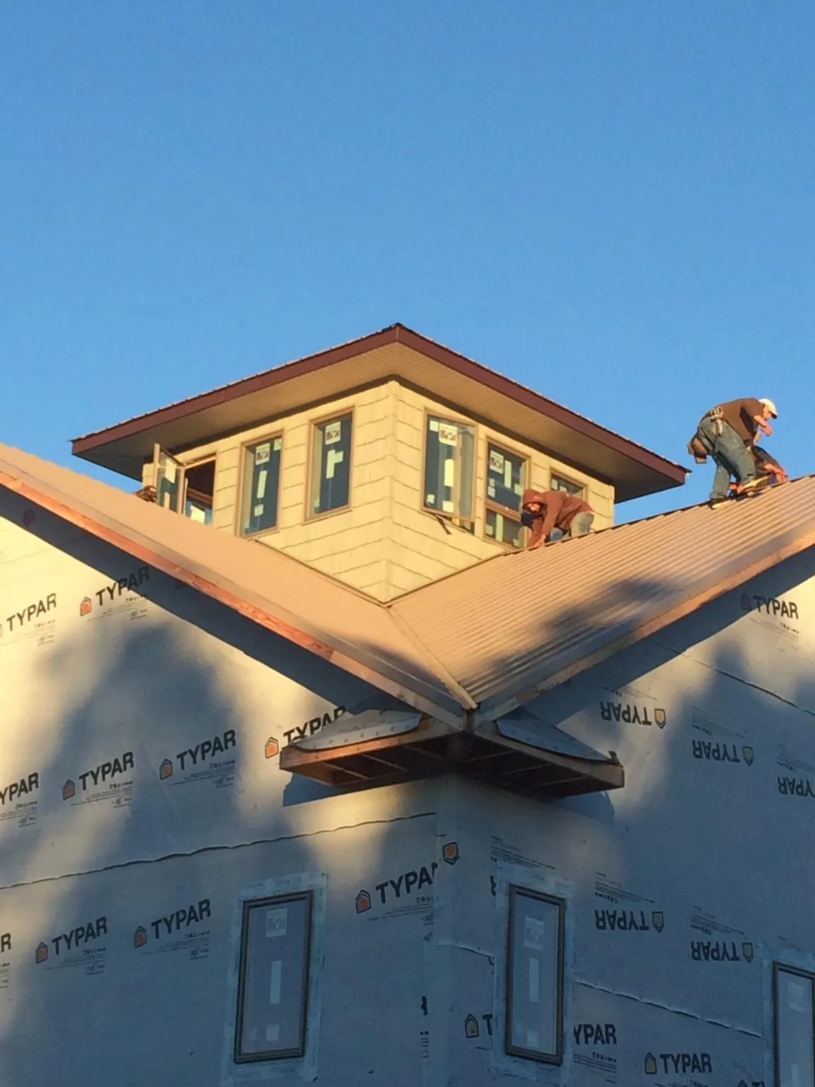 Roofers working around a rooftop cupola on a new metal roof at sunset — Roof Waterproofing in Waltersburg by Roofing Brothers